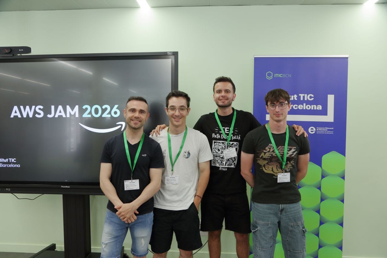 El equipo S3-less, cuatro integrantes con acreditación, posa junto a la pantalla de AWS JAM 2026 en el Institut TIC de Barcelona