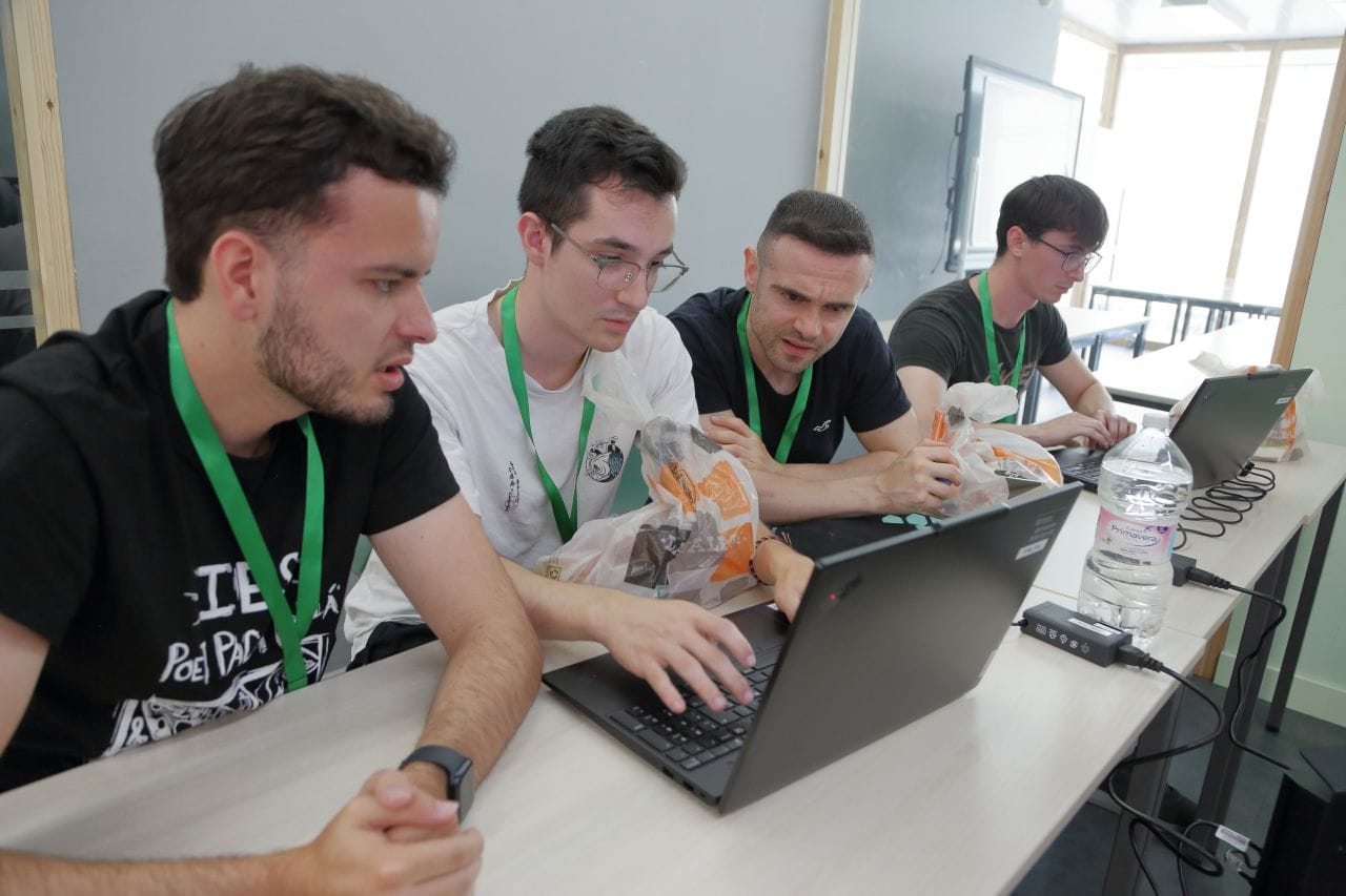 Los cuatro integrantes del equipo trabajando juntos en un portátil durante los retos de la final